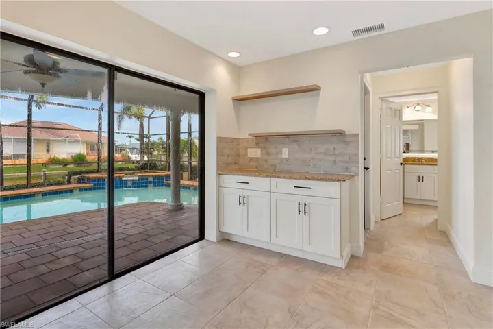 Kitchen with white cabinetry, light stone countertops, and backsplash
