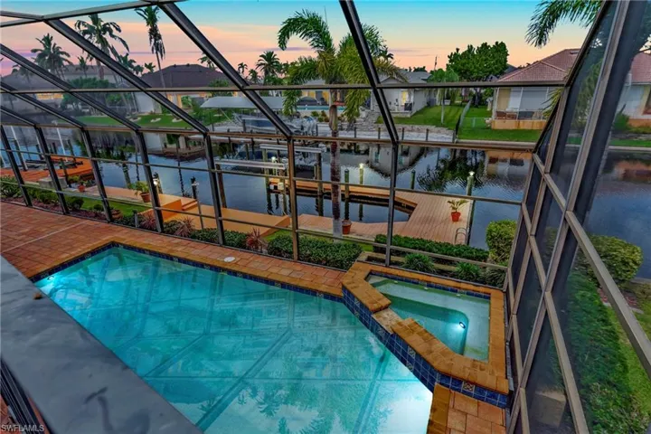 Pool at dusk with an in ground hot tub and a water view