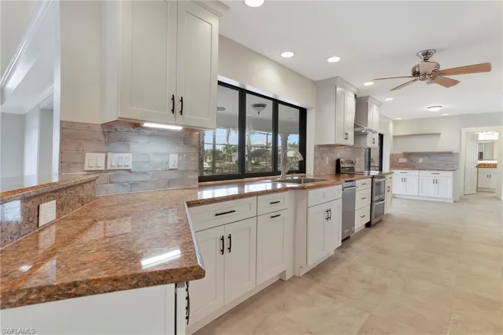 Kitchen featuring sink, ceiling fan, stainless steel appliances, tasteful backsplash, and white cabinets