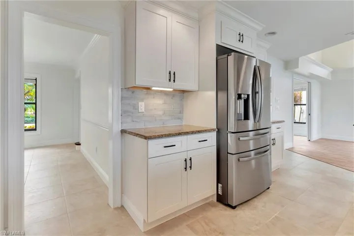 Kitchen with white cabinetry, stainless steel fridge, tasteful backsplash, and a wealth of natural light