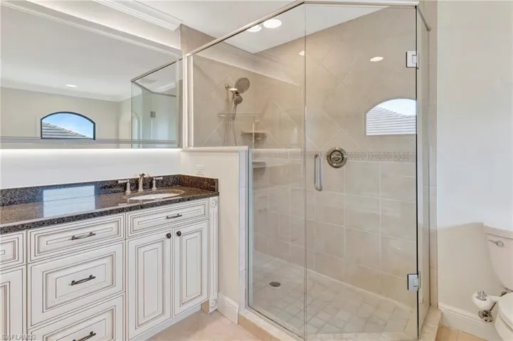 Bathroom featuring crown molding, tile patterned floors, a shower with door, and vanity