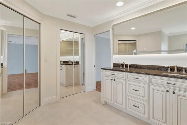 Bathroom with mirror closet doors leading to walk in closet