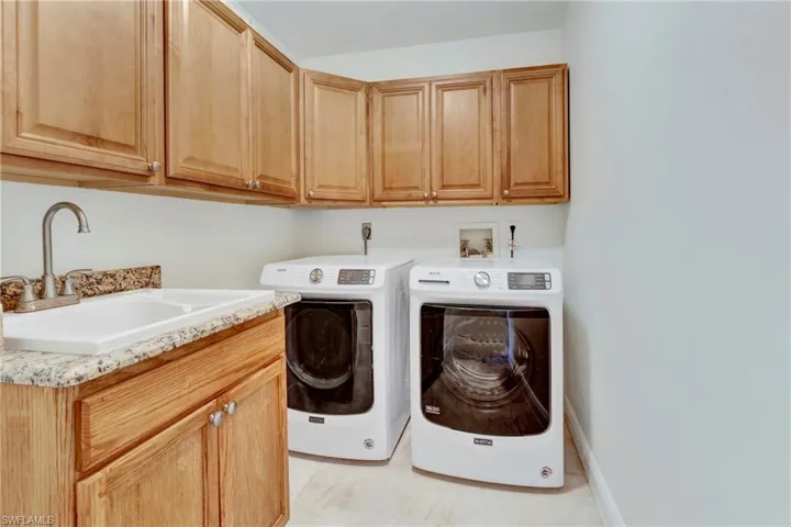 Laundry room with cabinets, separate washer and dryer, and sink
