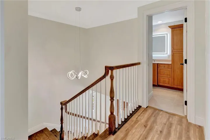 Staircase with an inviting chandelier, wood-type flooring, and crown molding