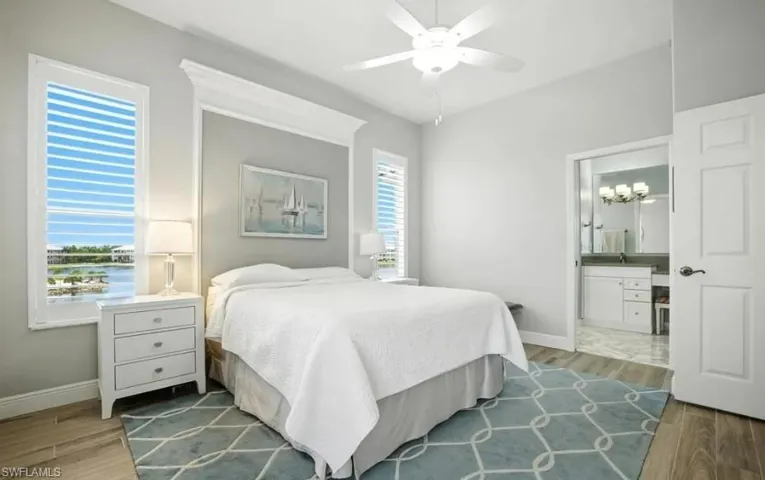 Bedroom with wood finished floors, a ceiling fan, and ensuite bathroom