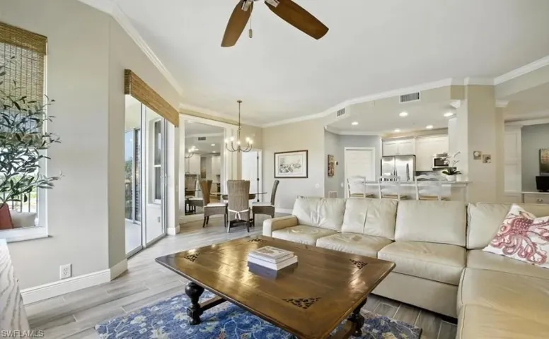 Living room with ceiling fan, crown molding, wood tiled floors, and a chandelier