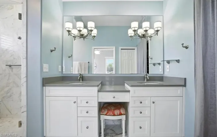 Bathroom featuring a marble finish shower, double vanity, a chandelier, and a ceiling fan