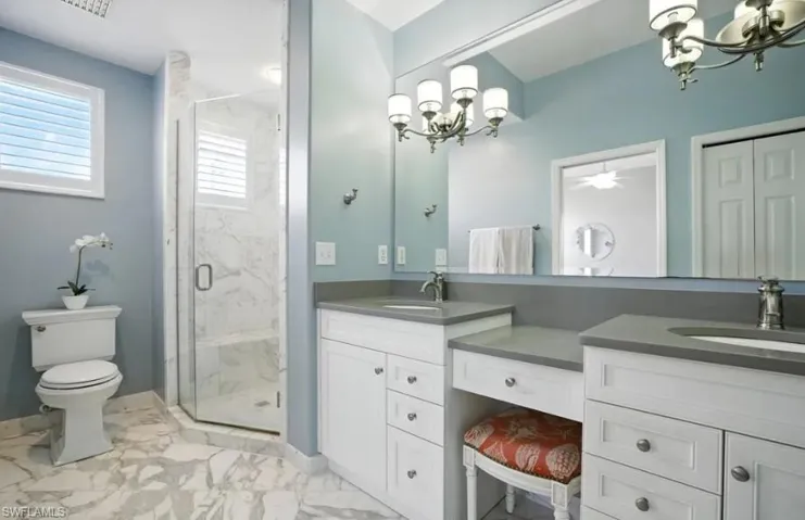 Bathroom featuring a chandelier, double vanity, a marble finish shower, and light marble finish flooring