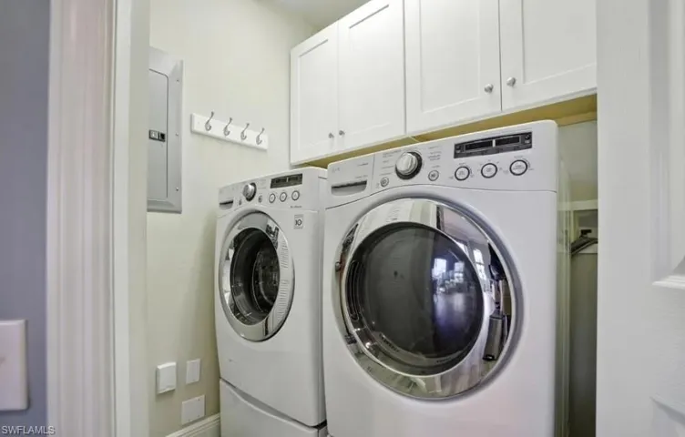 Laundry area featuring cabinet space, electric panel, and washing machine and clothes dryer