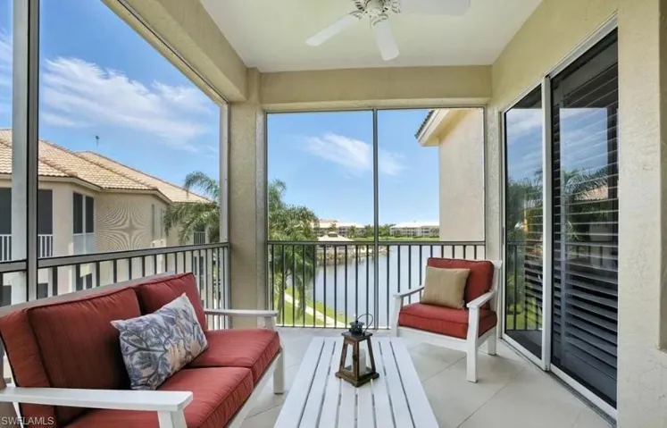 Sunroom featuring a balcony, ceiling fan, a water view, and tile patterned flooring