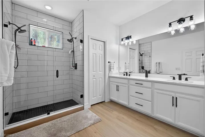 Bathroom featuring double vanity, a stall shower, light wood-type flooring, and a closet