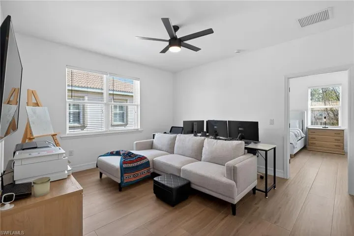 Living room with light wood-style flooring, healthy amount of natural light, and ceiling fan