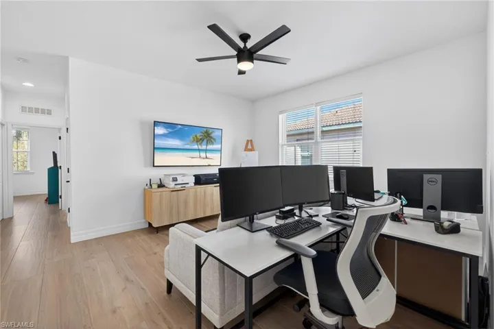 Office with light wood-style flooring and ceiling fan