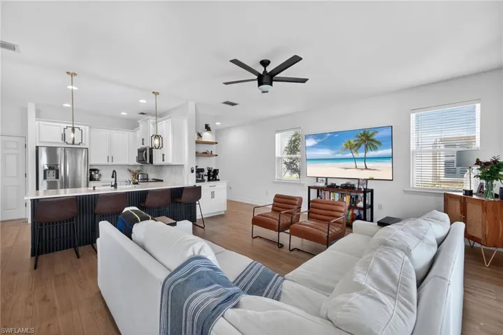 Living room with light wood-type flooring, a ceiling fan, and recessed lighting