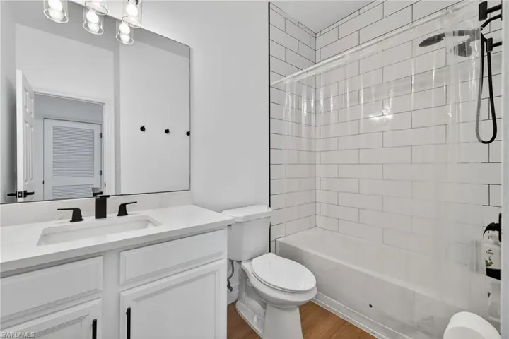 Bathroom featuring vanity, washtub / shower combination, and dark wood-type flooring