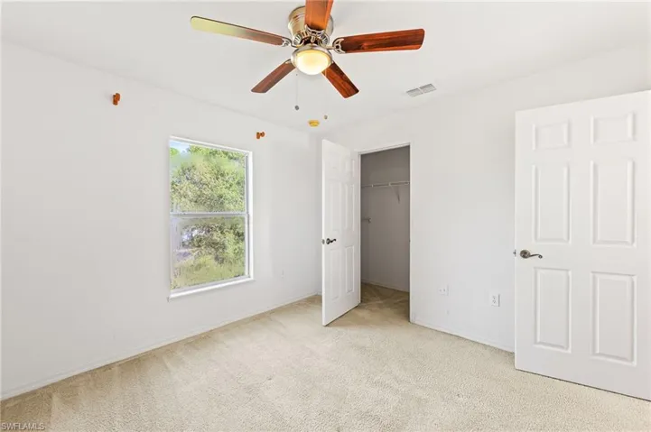 Unfurnished bedroom with light colored carpet, ceiling fan, and a closet