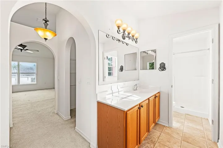 Bathroom featuring a shower stall, vanity, plenty of natural light, and ceiling fan