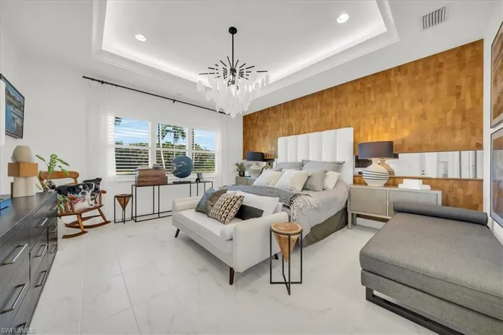 Bedroom with an accent wall, light marble finish floors, recessed lighting, a chandelier, and a raised ceiling