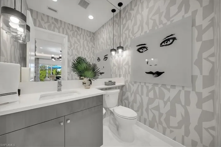 Bathroom featuring wallpapered walls, vanity, recessed lighting, and light marble finish flooring