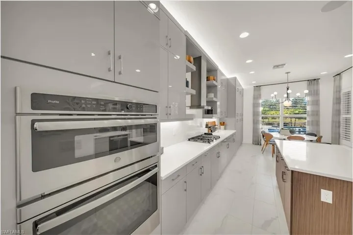 Kitchen with pendant lighting, open shelves, appliances with stainless steel finishes, recessed lighting, and a chandelier