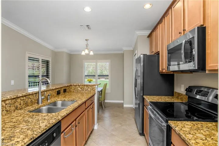 Kitchen includes large island, stainless steel appliances, kitchen cafe, and a pantry for additional storage.