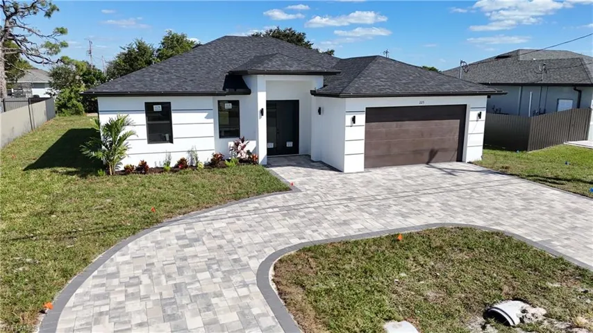 View of front of property with roof with shingles, decorative driveway, and stucco siding