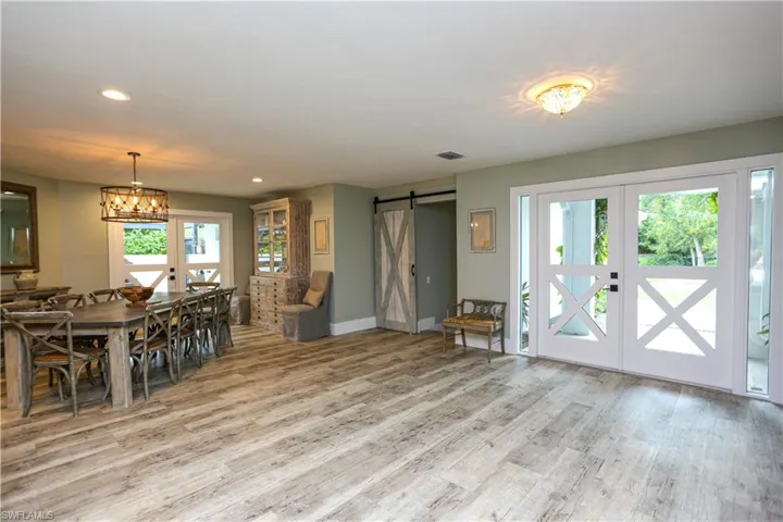 Dining space with a barn door, recessed lighting, light wood-style floors, french doors, and a chandelier