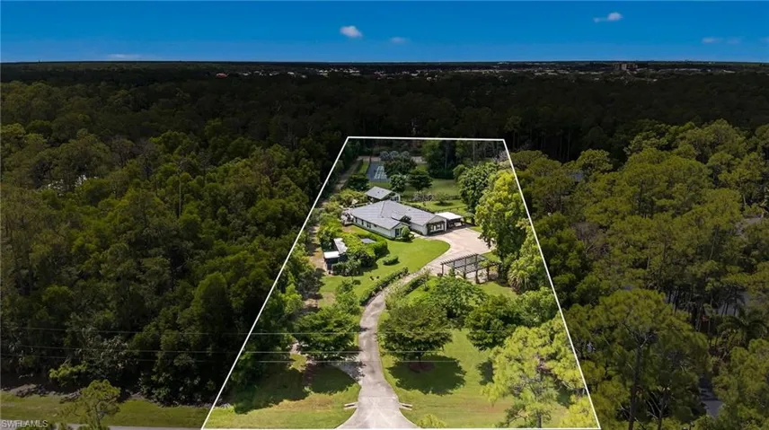 Aerial view of property and surrounding area featuring a heavily wooded area and property parcel outlined