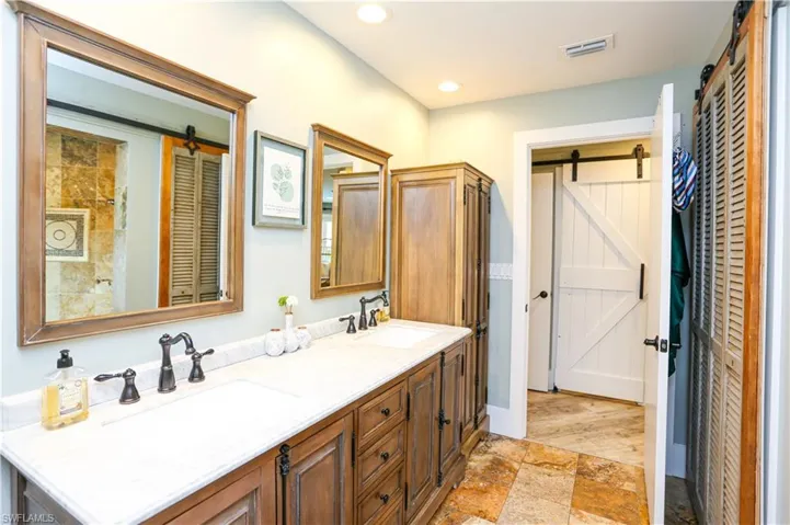Full bath with double vanity, stone tile flooring, and recessed lighting