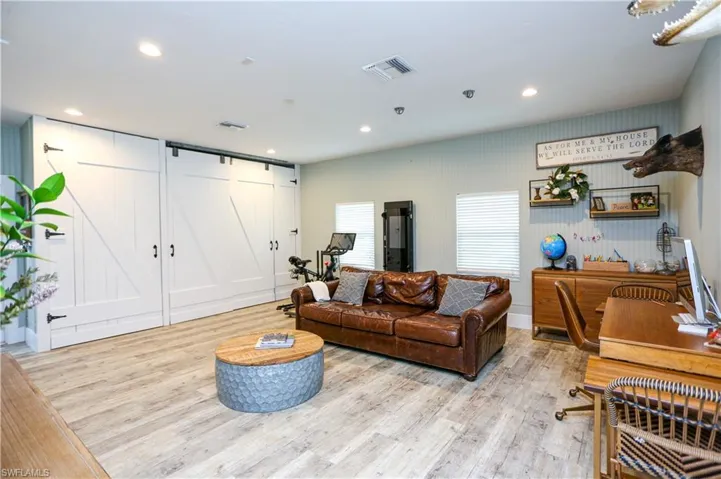 Living room featuring a barn door, light wood-style floors, and recessed lighting