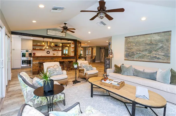 Living room with vaulted ceiling, light wood-type flooring, recessed lighting, and a ceiling fan