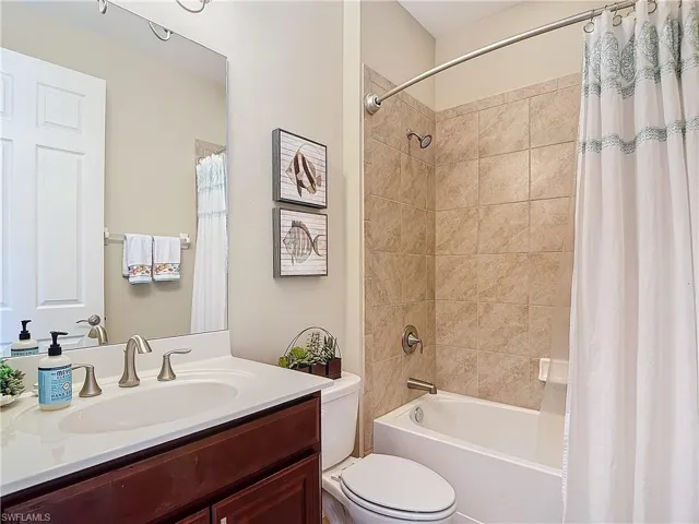 Full bathroom featuring shower / bath combination with curtain, toilet, and vanity