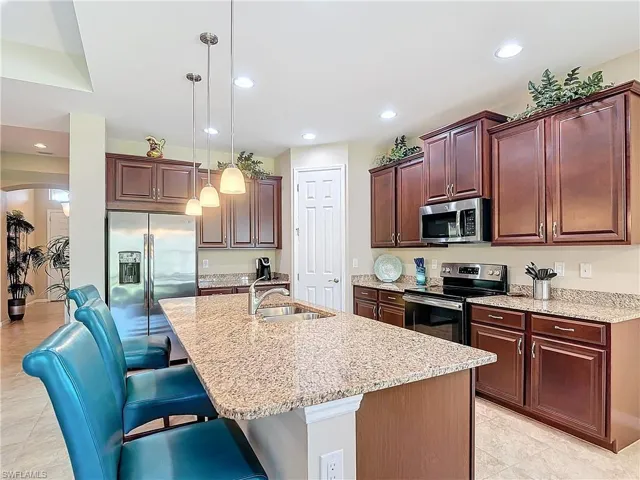 Kitchen featuring a center island with sink, stainless steel appliances, sink, and hanging light fixtures