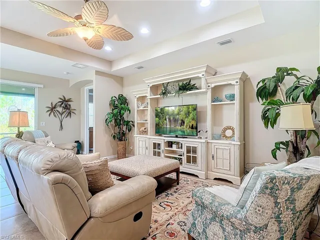 Tiled living room with ceiling fan and a tray ceiling