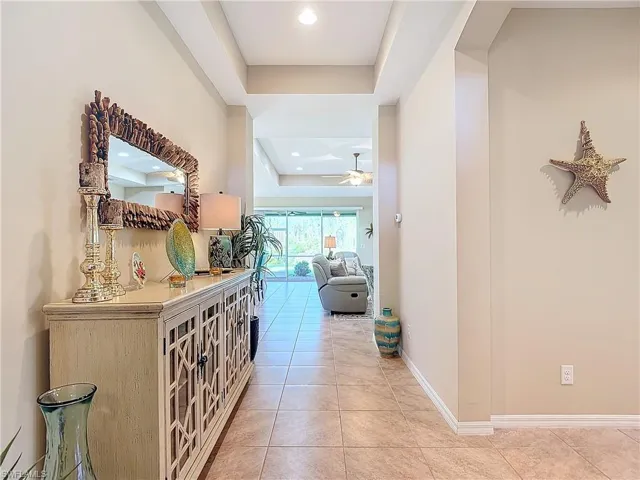 Hallway with a tray ceiling and light tile patterned floors