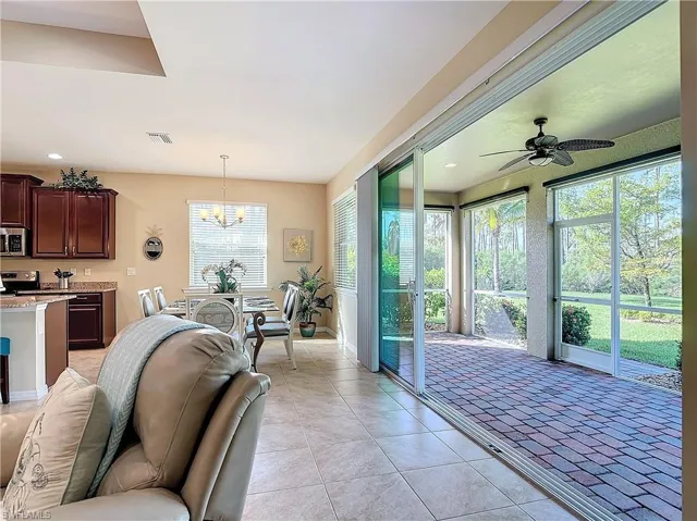 Tiled living room with ceiling fan with notable chandelier and plenty of natural light