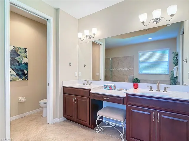 Bathroom featuring tile patterned flooring, vanity, toilet, and a tile shower