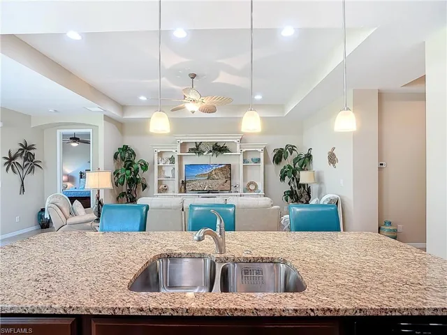 Kitchen featuring a tray ceiling, sink, ceiling fan, and hanging light fixtures