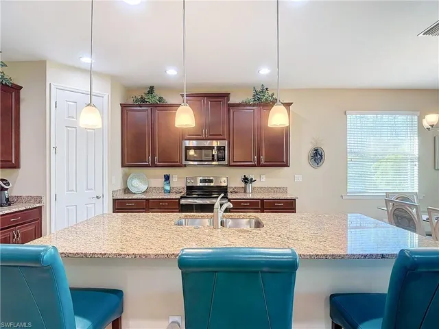 Kitchen featuring appliances with stainless steel finishes, a breakfast bar area, sink, and hanging light fixtures