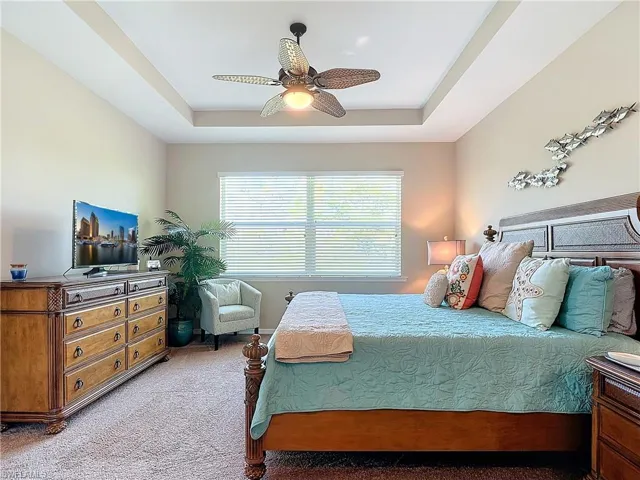 Bedroom with carpet flooring, a tray ceiling, and ceiling fan
