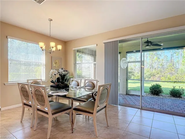 Tiled dining space with ceiling fan with notable chandelier and a healthy amount of sunlight