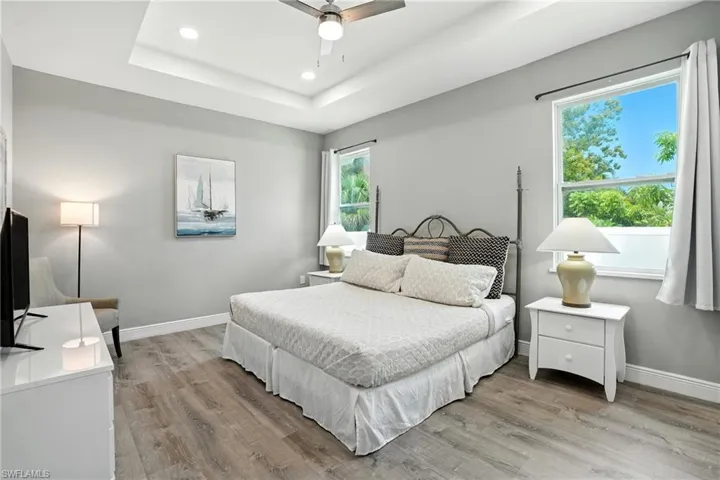 Bedroom featuring light wood finished floors, ceiling fan, recessed lighting, and a raised ceiling