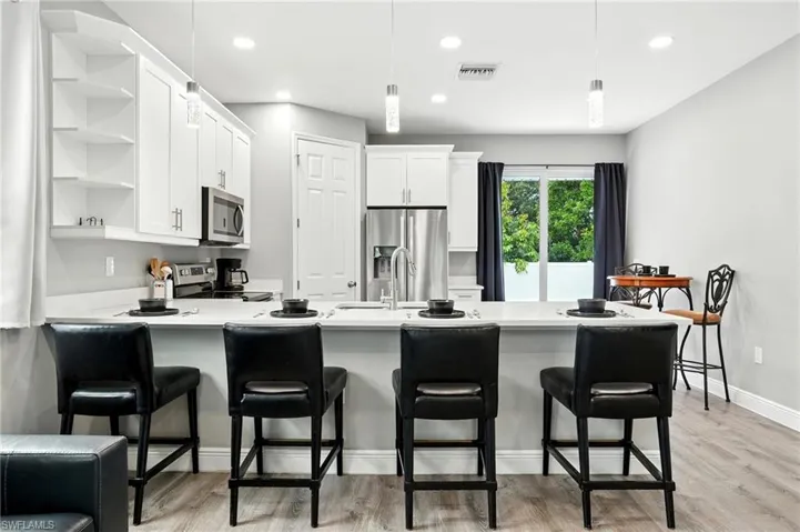 Kitchen with a peninsula, open shelves, white cabinets, light wood-style flooring, and recessed lighting