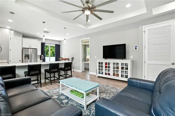 Living area featuring a tray ceiling, recessed lighting, light wood-style flooring, and a ceiling fan