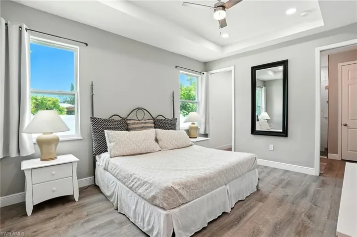 Bedroom featuring light wood-type flooring, recessed lighting, ceiling fan, and a raised ceiling