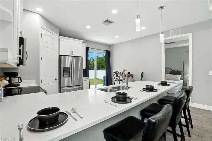 Kitchen featuring a peninsula, a breakfast bar, appliances with stainless steel finishes, light wood finished floors, and recessed lighting