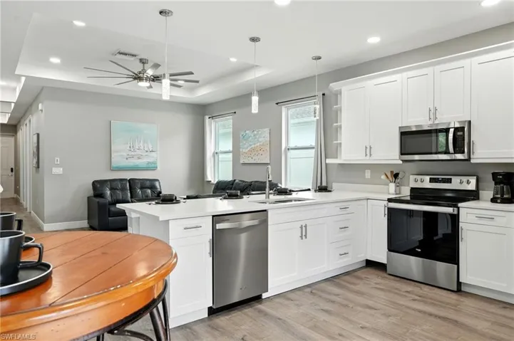 Kitchen with appliances with stainless steel finishes, open floor plan, white cabinets, recessed lighting, and light wood-style floors