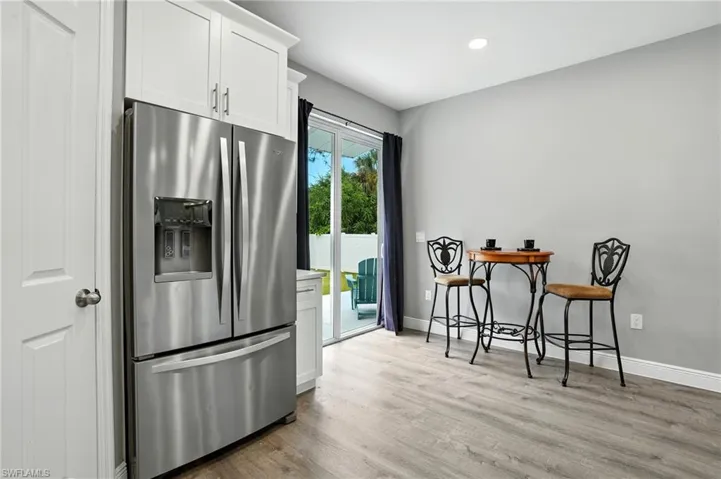 Kitchen with stainless steel refrigerator with ice dispenser, white cabinetry, light wood-style flooring, recessed lighting, and light countertops