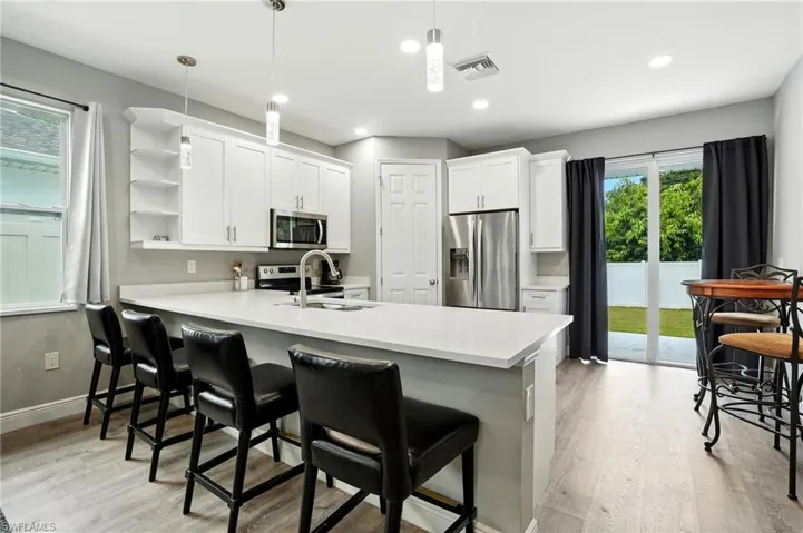 Kitchen with appliances with stainless steel finishes, open shelves, white cabinetry, light wood-style floors, and recessed lighting