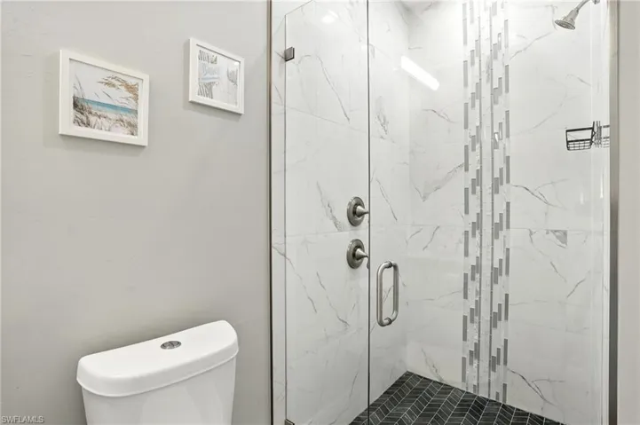 Bathroom with a marble finish shower and toilet